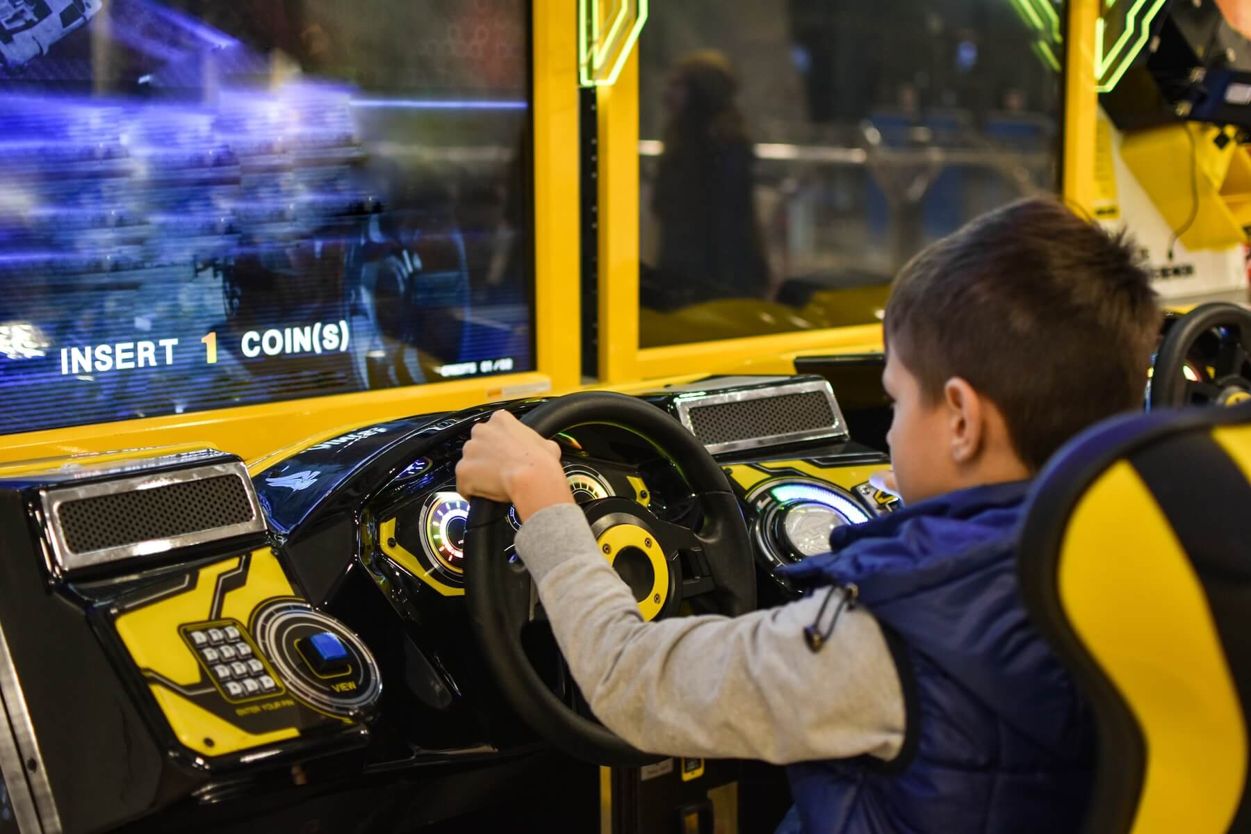 boy playing driving game in the arcade