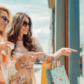 Happy woman with shopping bags pointing finger in the shop window.
