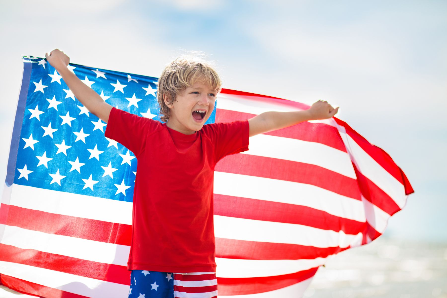 kid holding american flag on the beach